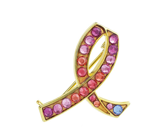 La broche Ruban Rose Estée Lauder se pare d’une pierre bleue pour représenter les 1 % de cas de cancer du sein diagnostiqués chez les hommes aux États-Unis.